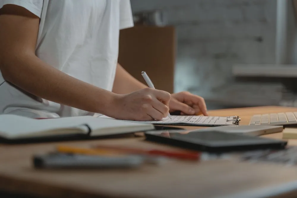 Someone working through a checklist on a clipboard at a desk.
