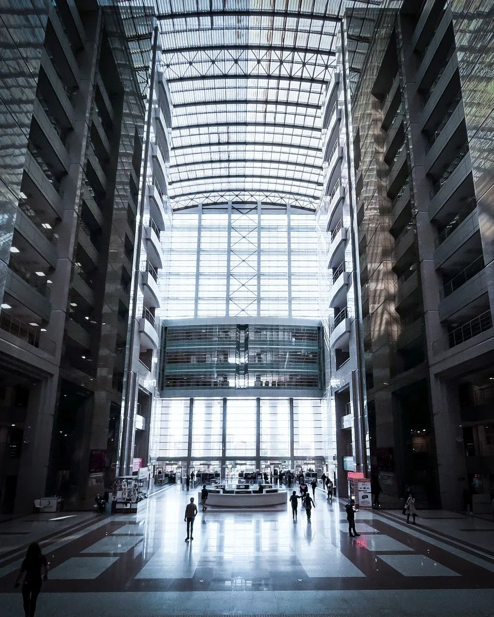 People crossing the bright atrium of a busy commercial building.