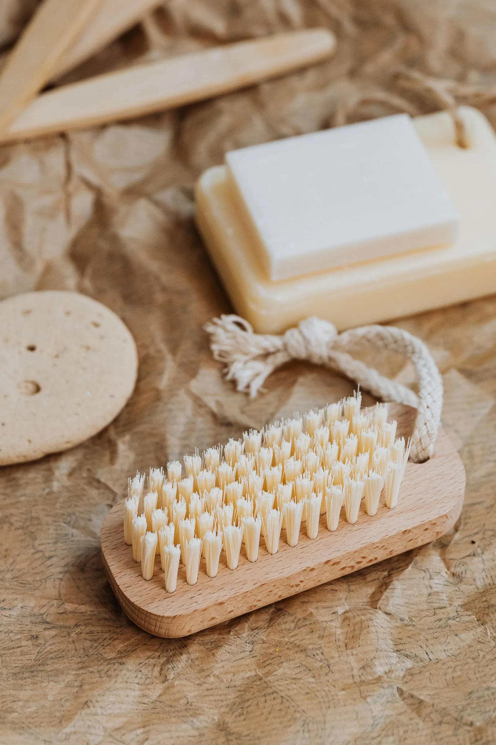 Wooden brushes, natural soap, and a sponge on kraft paper.